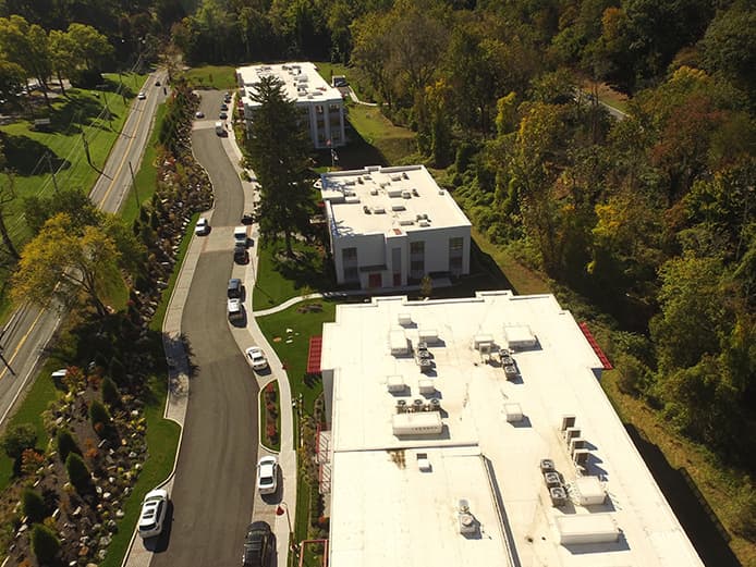 An aerial view of three residential buildings backed by trees.